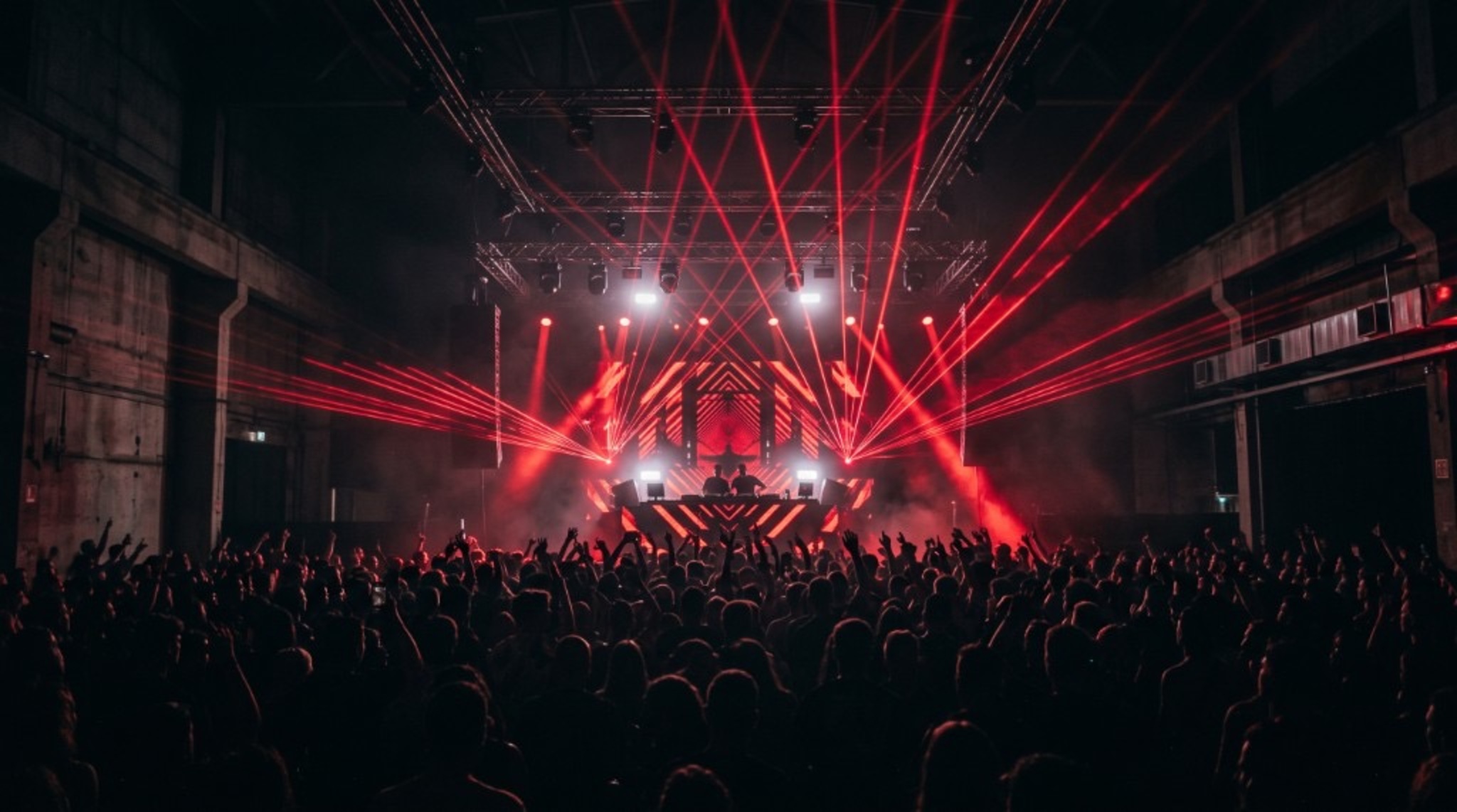 Pista lotada iluminada por lasers vermelhos em um show de música eletrônica